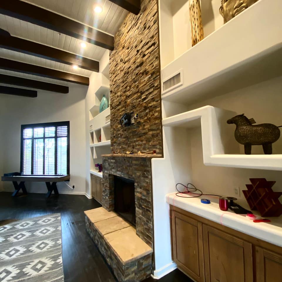A living room with a stone fireplace and shelves