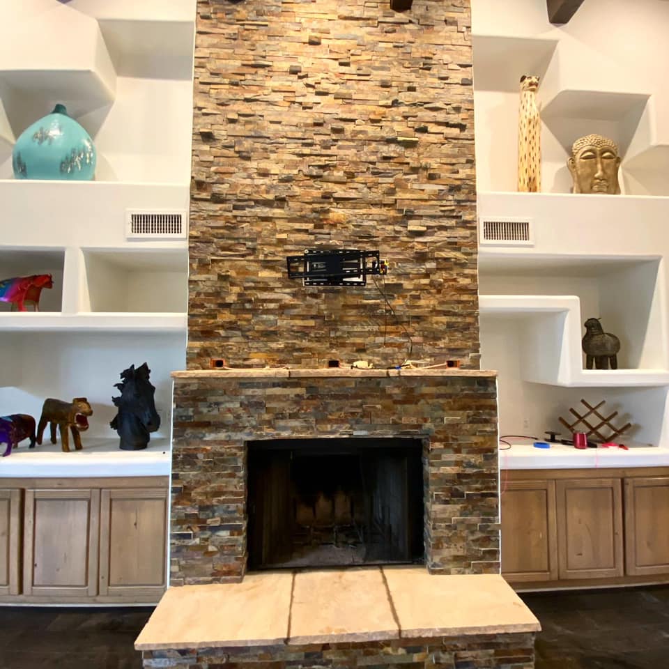 A living room with a stone fireplace and shelves