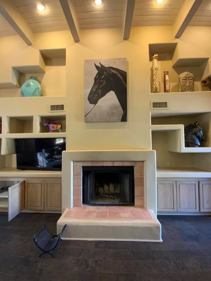 A living room with a fireplace and a painting of a horse on the wall