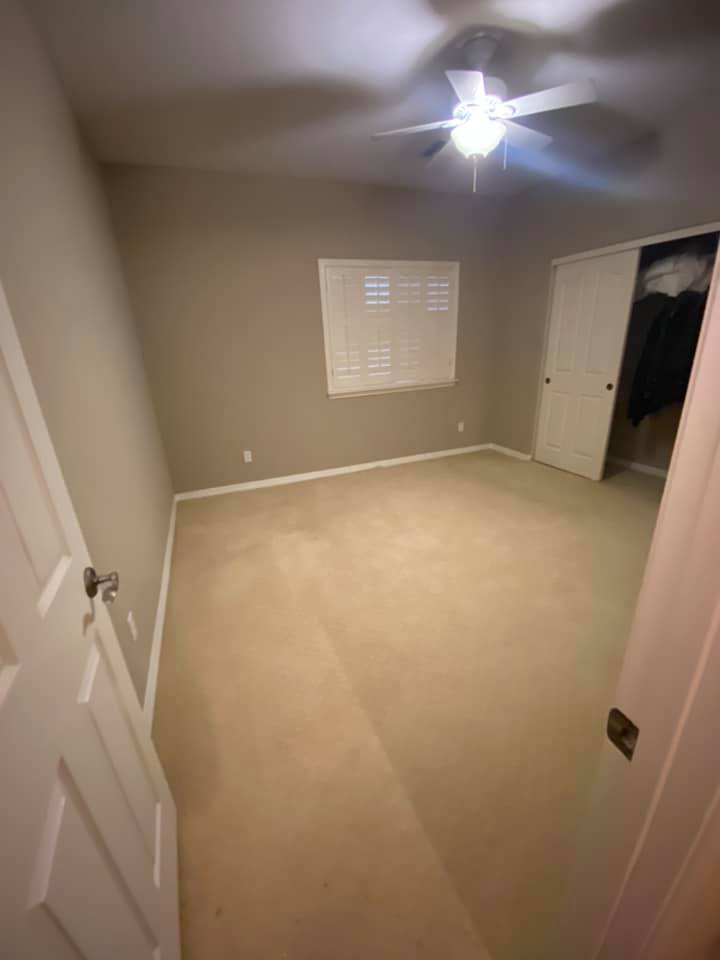 An empty bedroom with a ceiling fan and a window.
