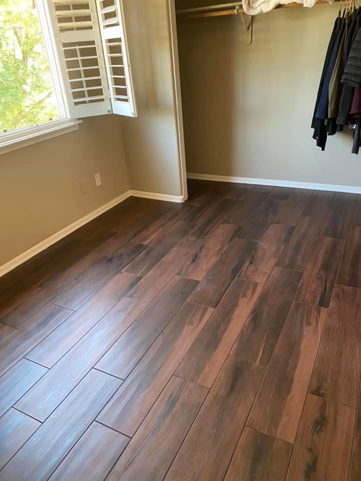 A bedroom with hardwood floors and a window with shutters.