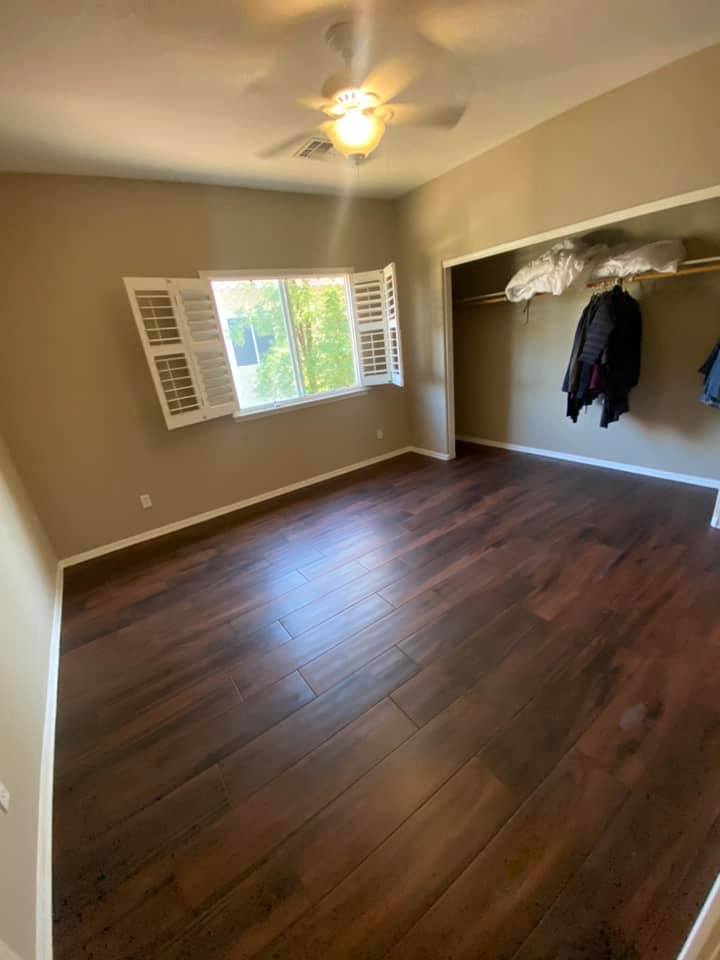 A bedroom with hardwood floors and a ceiling fan.