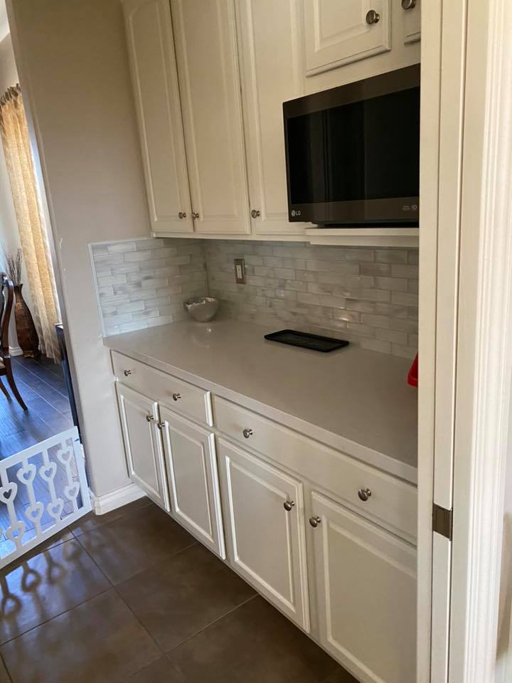 A kitchen with white cabinets and a microwave.