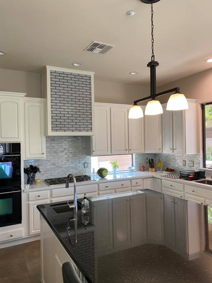 A kitchen with white cabinets and a black counter top.