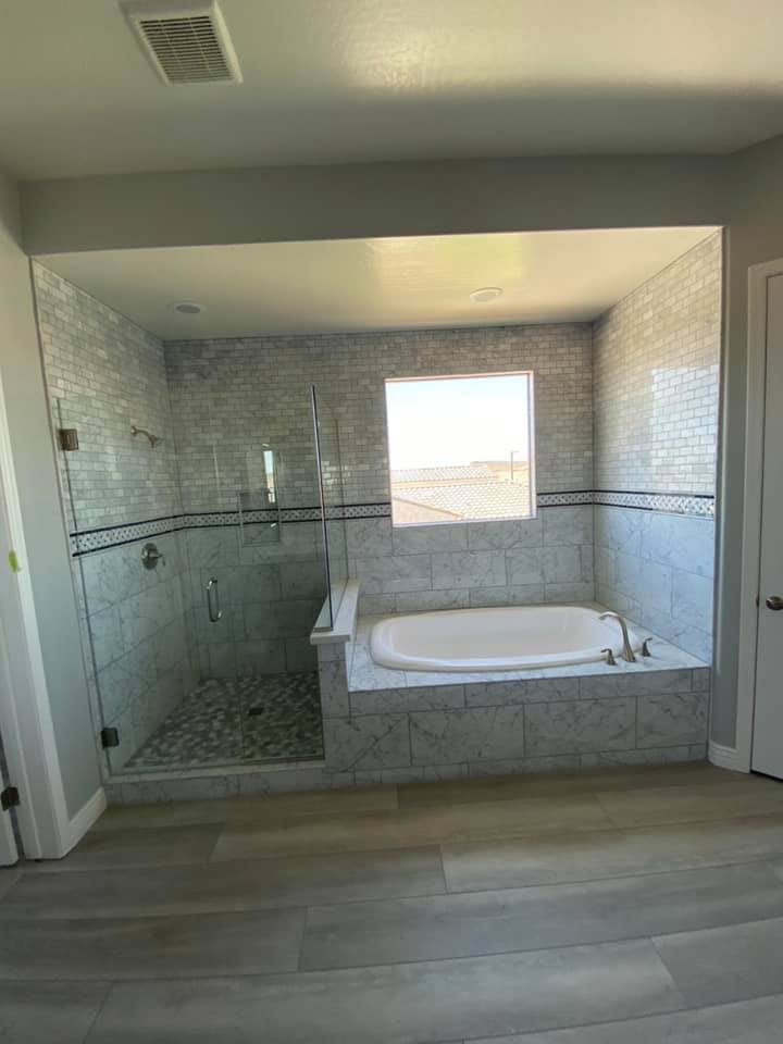 A bathroom with a tub , shower , and window.