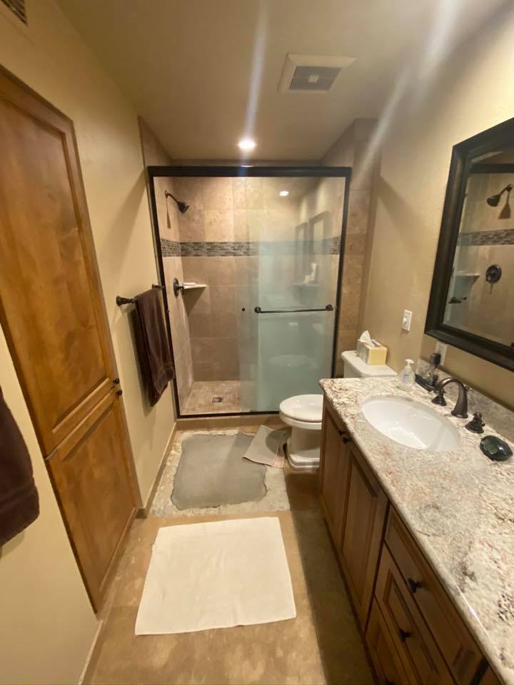 A bathroom with a toilet , sink , mirror and walk in shower.