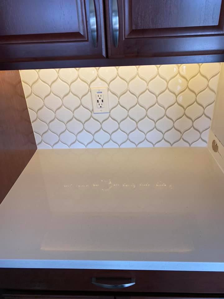 A kitchen counter with a white counter top and a white tile backsplash.