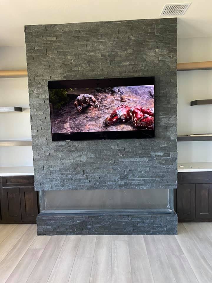 A living room with a fireplace and a flat screen tv mounted on the wall.