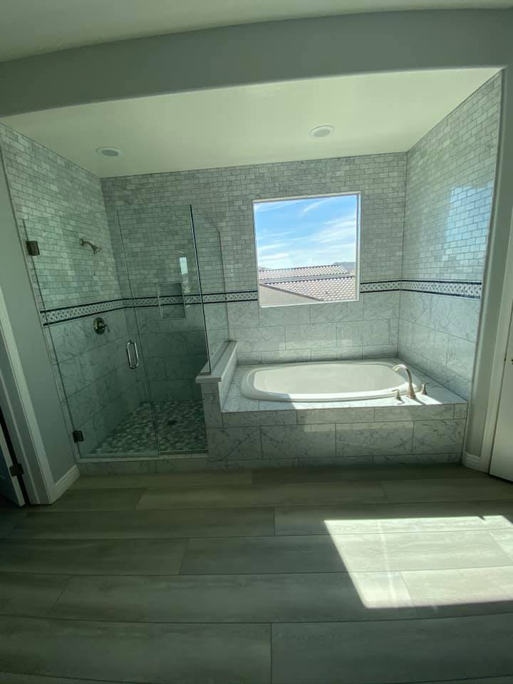 A bathroom with a tub , shower , and window.