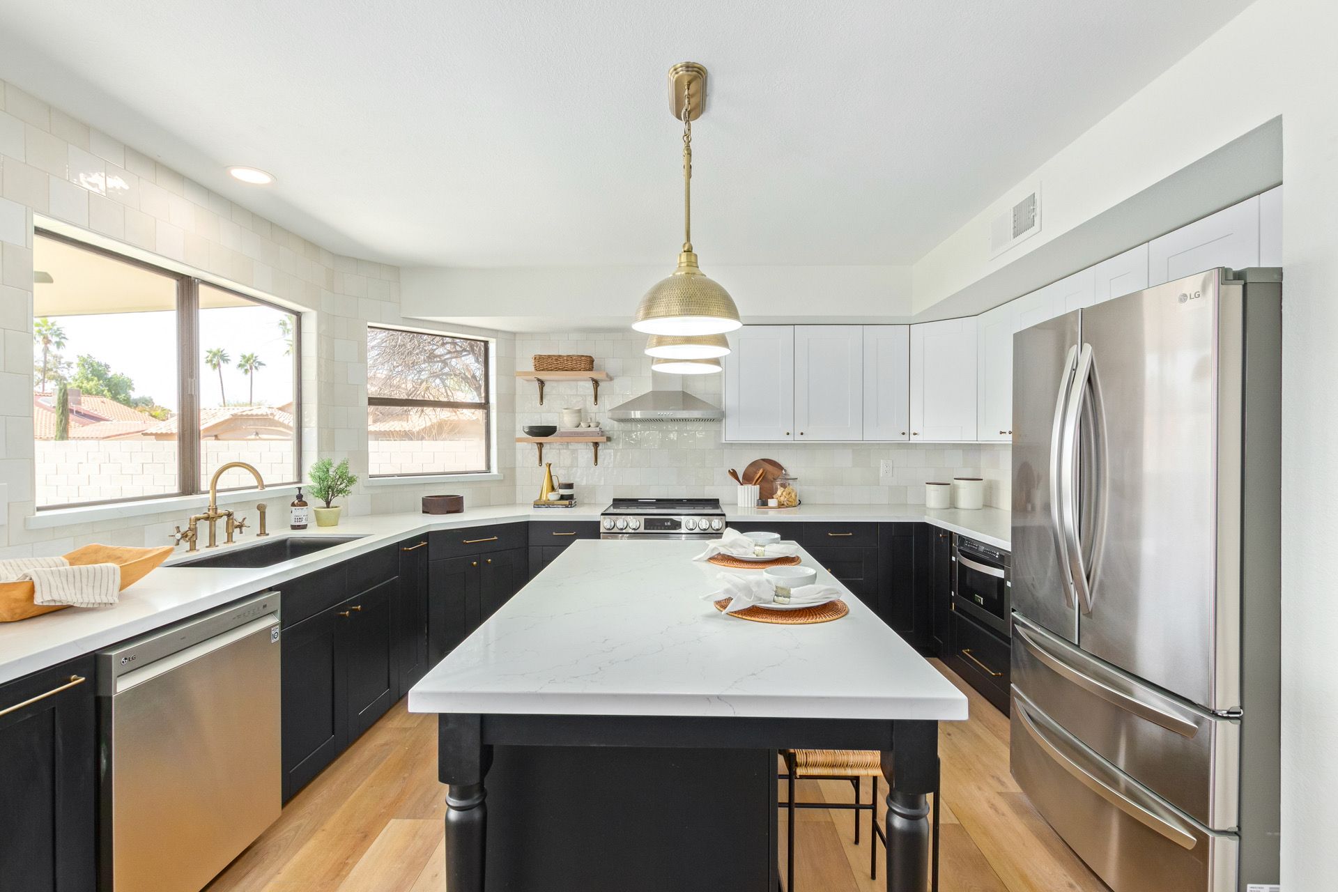 A kitchen with black cabinets , white counter tops , stainless steel appliances and a large island.