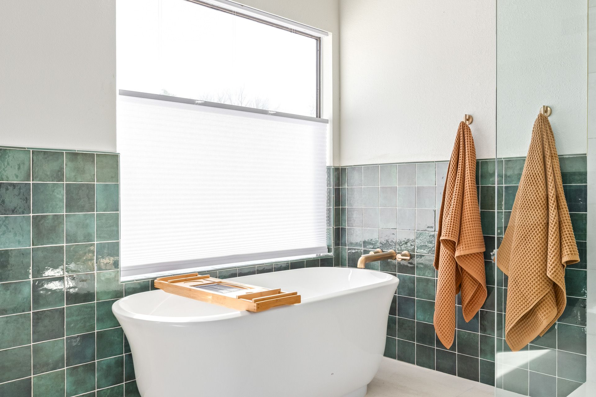 There is a bathtub in the bathroom with green tiles.