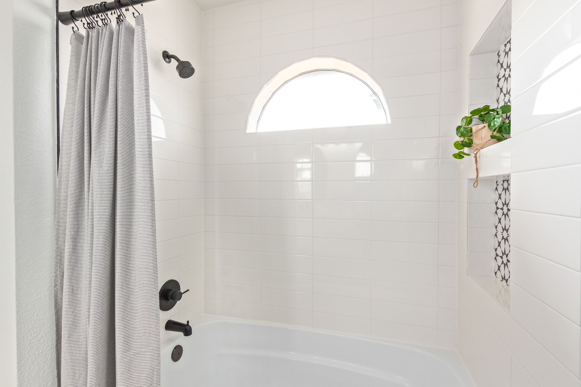 A bathroom with a bathtub , shower , and window.