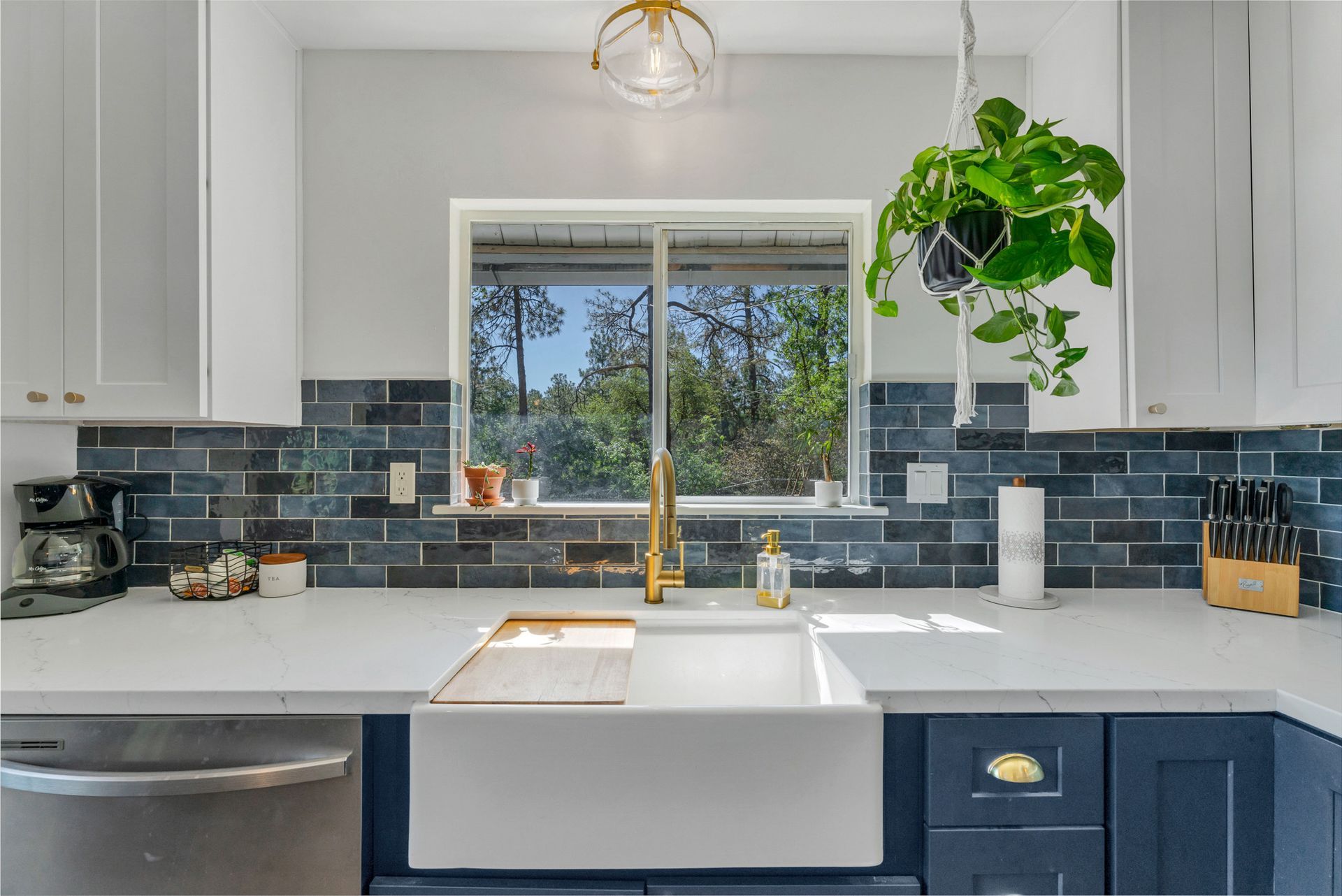 A kitchen with a sink , dishwasher , and window.