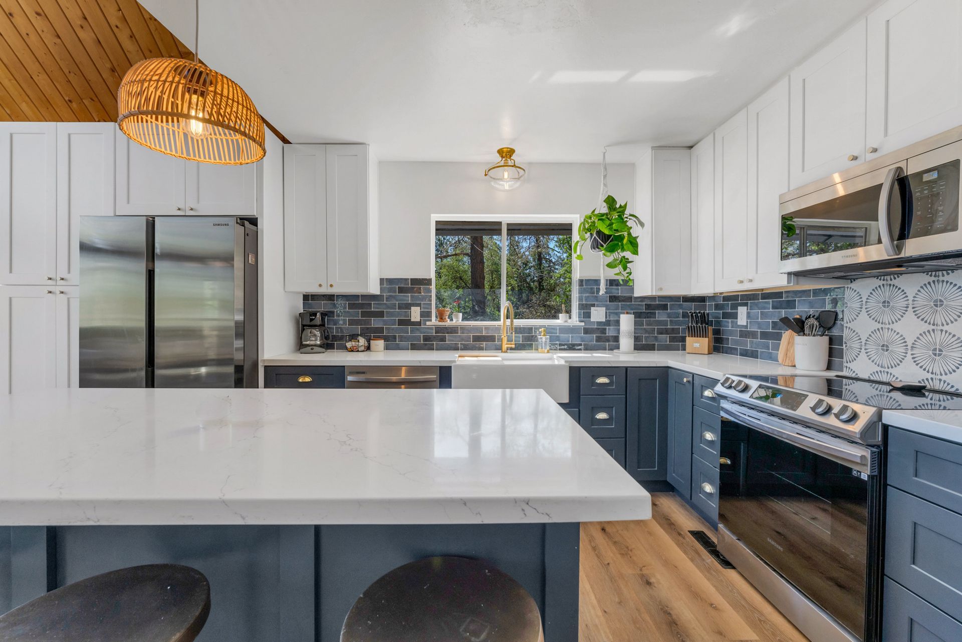A kitchen with blue cabinets , white cabinets , stainless steel appliances and a large island.