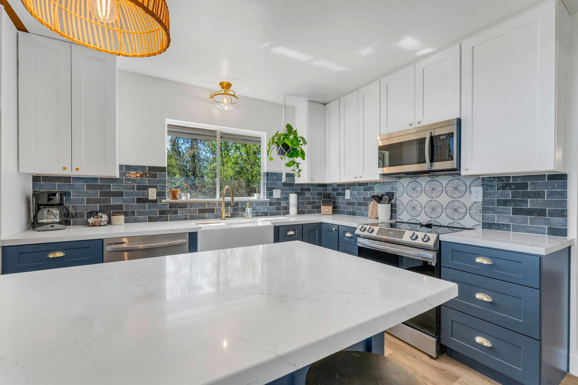 A kitchen with blue cabinets , white counter tops , stainless steel appliances and a large island.