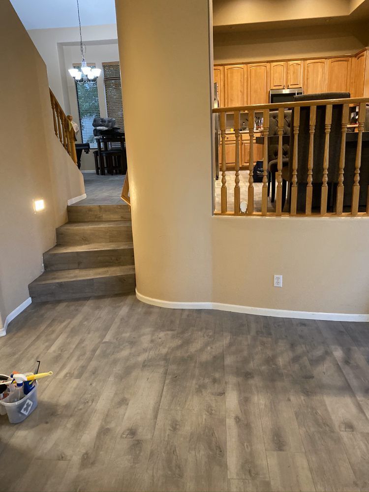 A living room with hardwood floors and stairs leading to a kitchen.