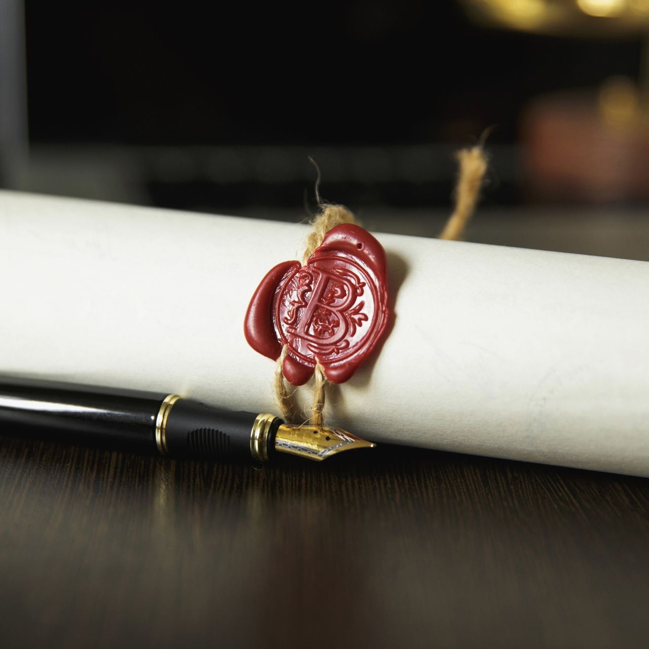 A scroll of paper with a red wax seal and a pen