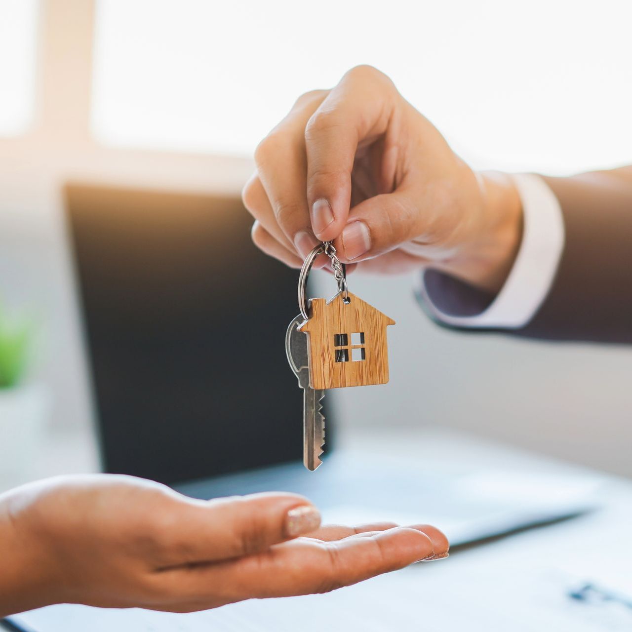 A person is handing a house key to another person.
