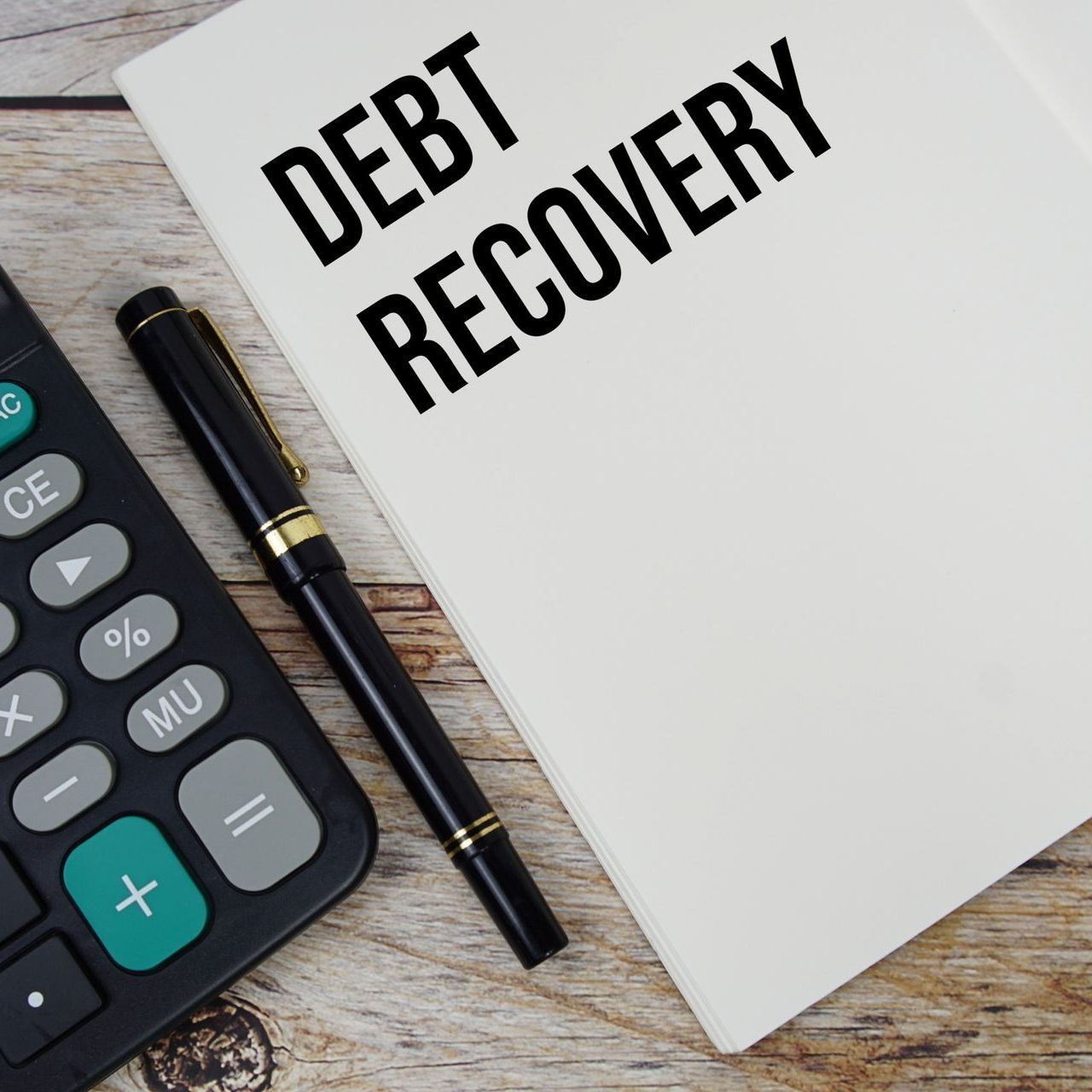 A notepad that says debt recovery next to a calculator and pen