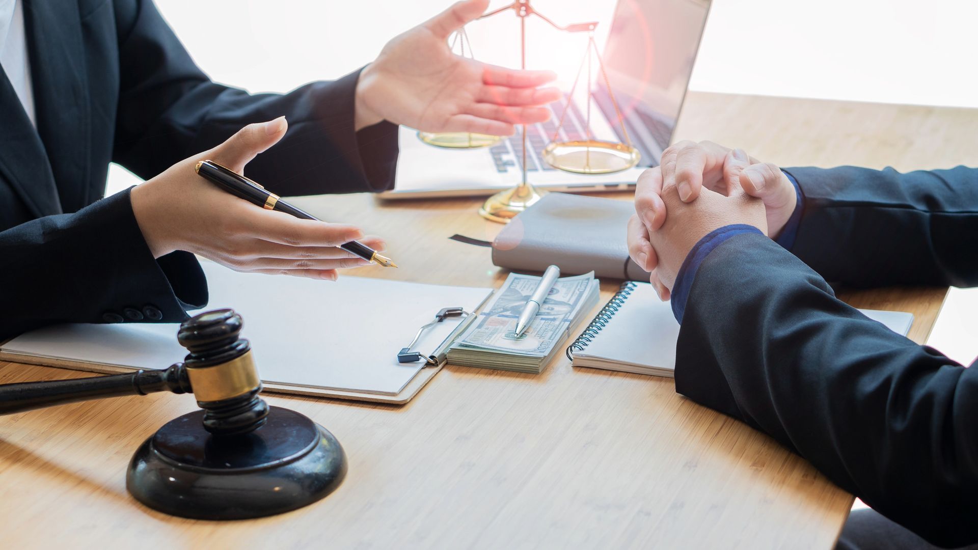 Lawyer pointing, explaining to a client, scales of justice, gavel on the table.