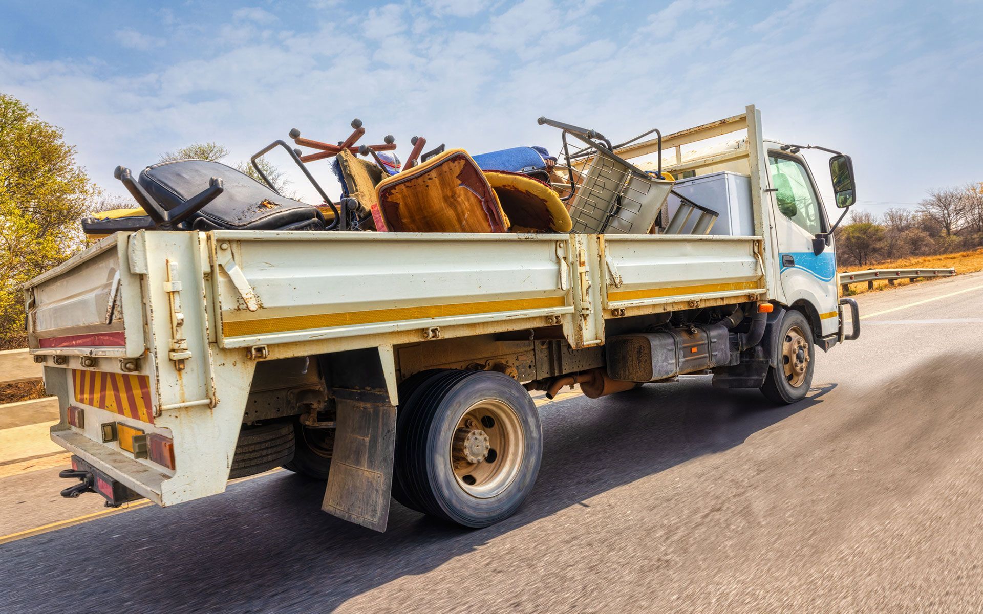 A white truck filled with furniture is driving down a road.