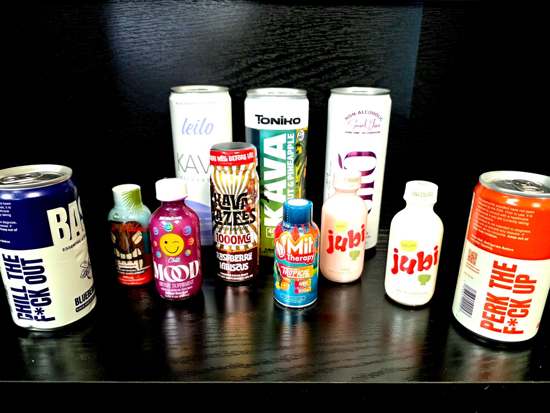 A shelf display of various relaxation and energy drinks in cans and small bottles against a black background.