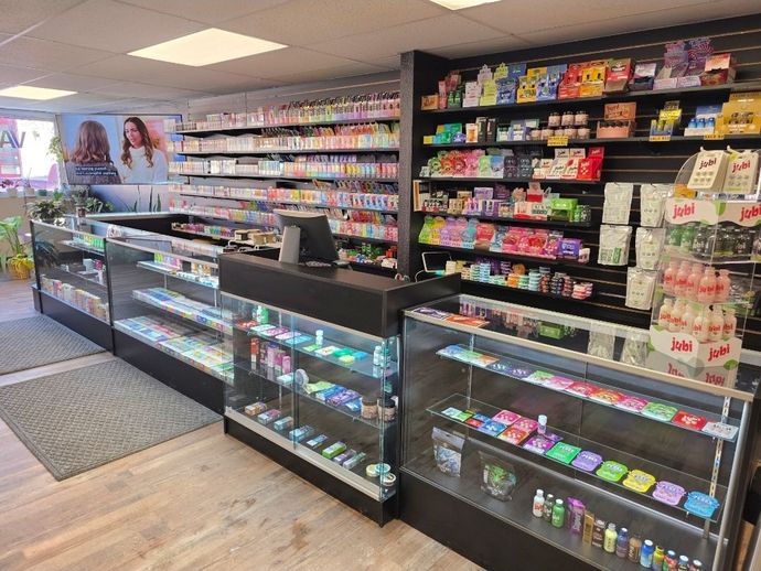 The interior of a convenience or vape shop featuring glass display cases and shelves stocked with various colorful products.