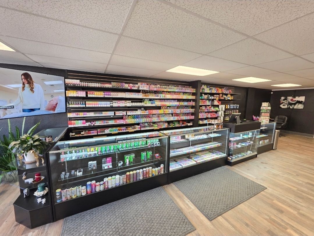 An interior view of a vape shop with rows of products displayed on wall shelves and inside glass cabinets.