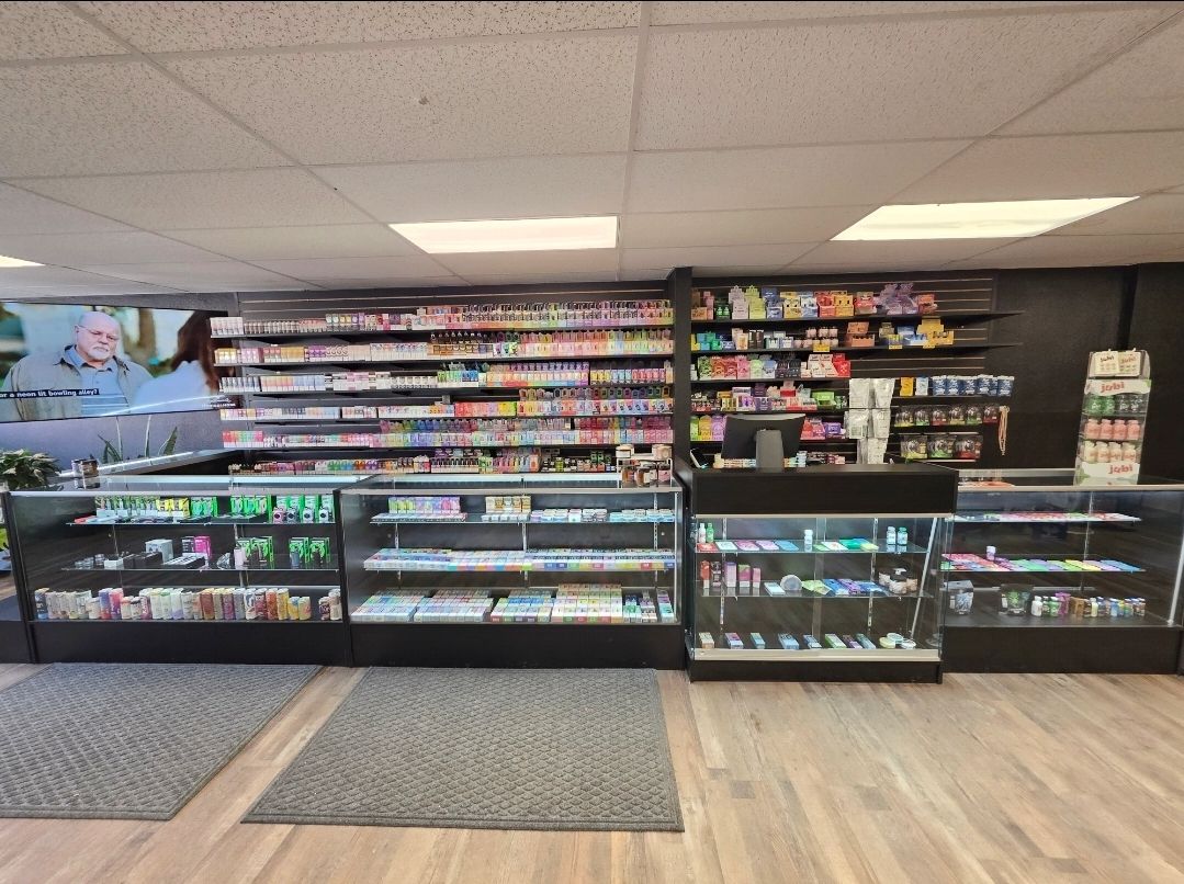 A retail store interior with rows of products on display shelves and behind several glass counter display cases.