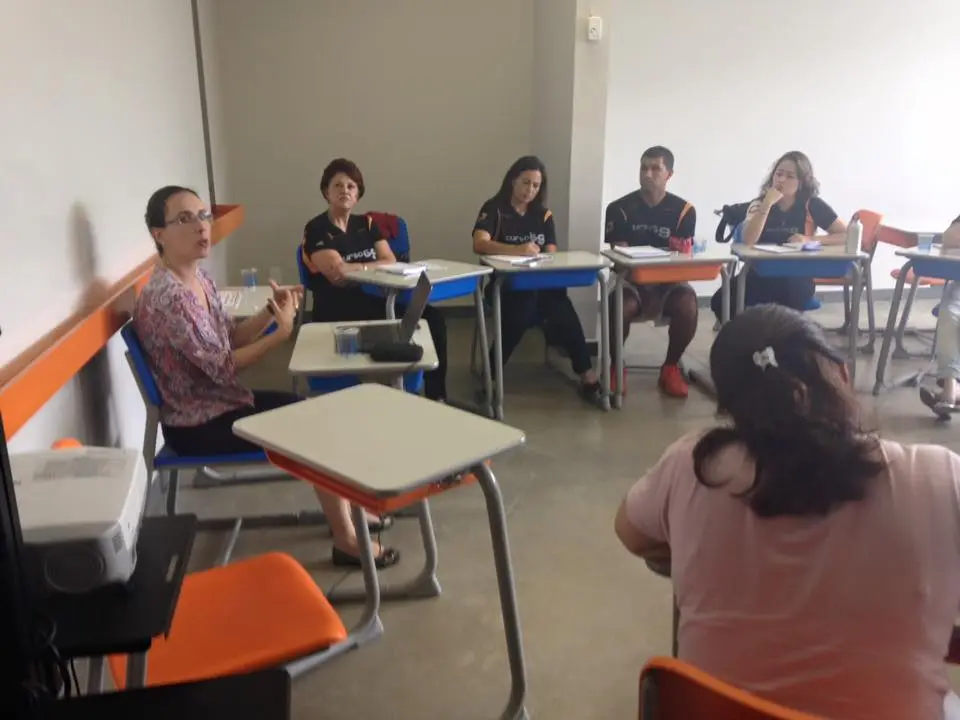 Um grupo de pessoas está sentado em carteiras em uma sala de aula