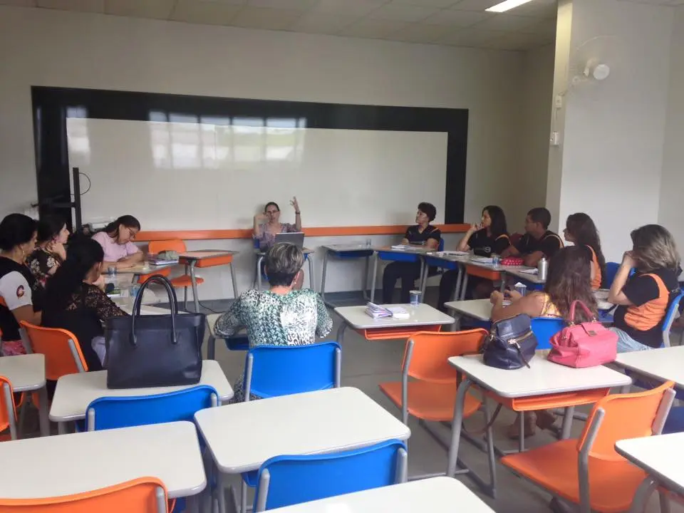 Um grupo de pessoas está sentado em carteiras em uma sala de aula.