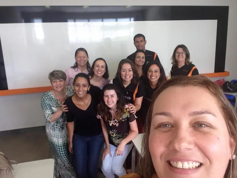 Um grupo de pessoas está posando para uma foto em uma sala de aula.