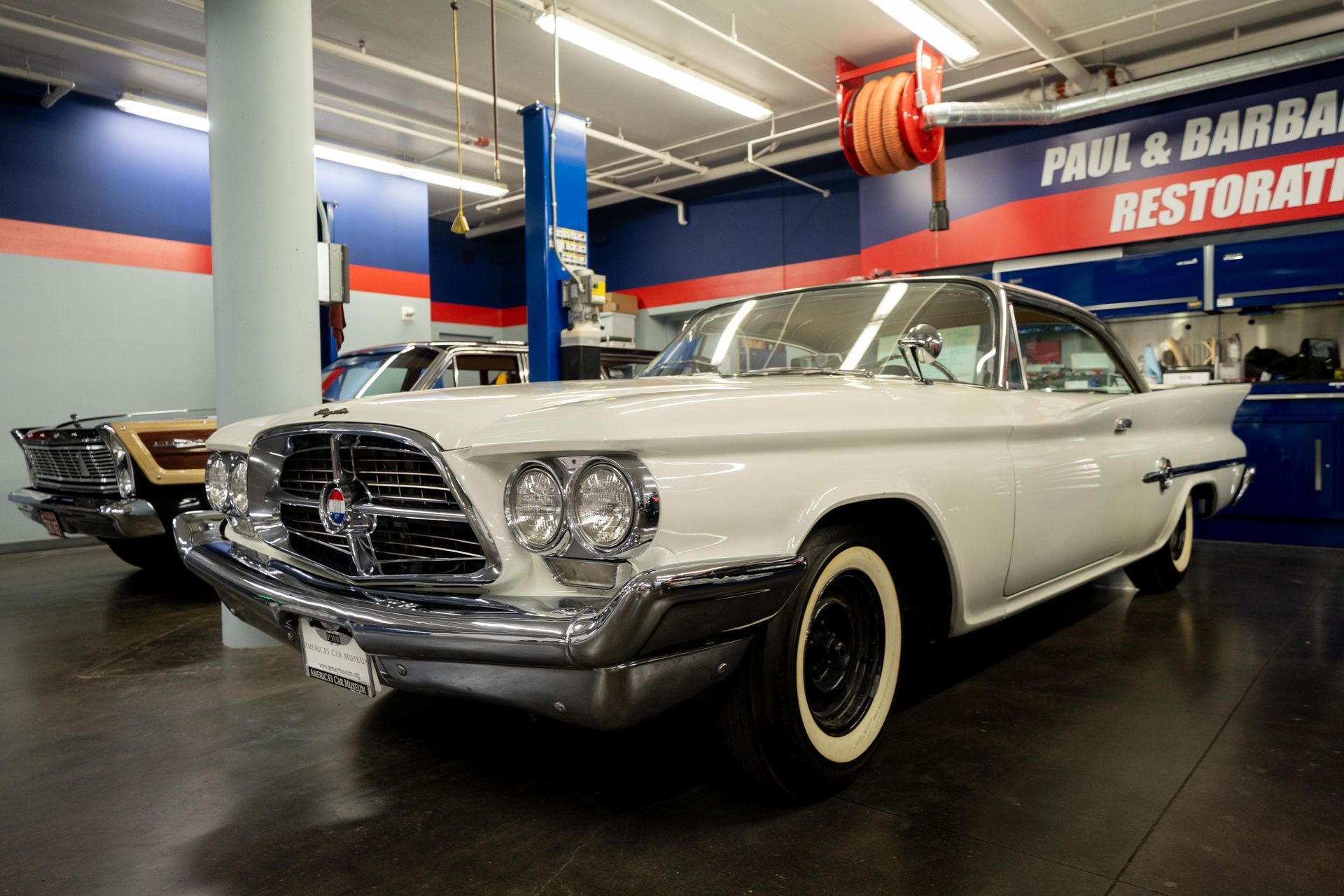 White classic car in a museum with blue accents.