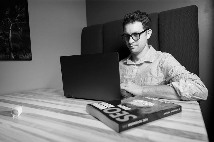 a laptop computer is sitting on a wooden table next to a piece of paper with a graph on it .