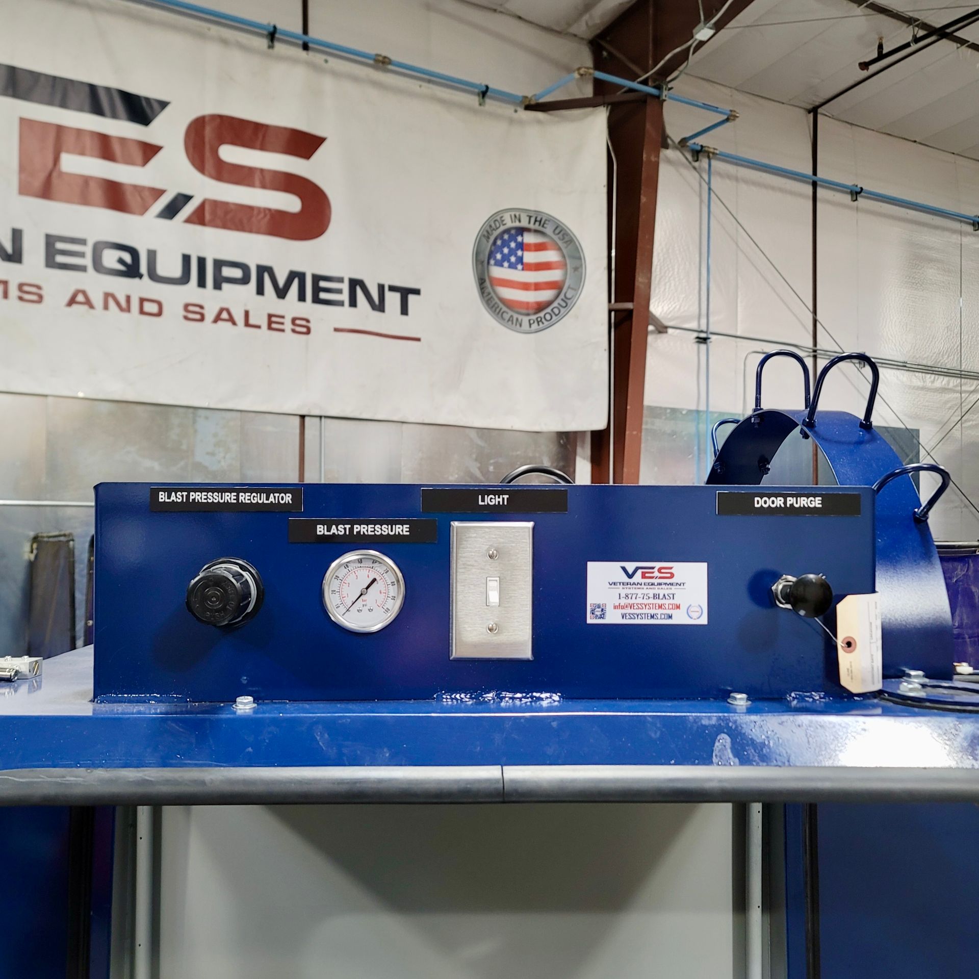 Blue machine with gauges and switch, banner above: “ES” logo with “EQUIPMENT” and American flag seal.