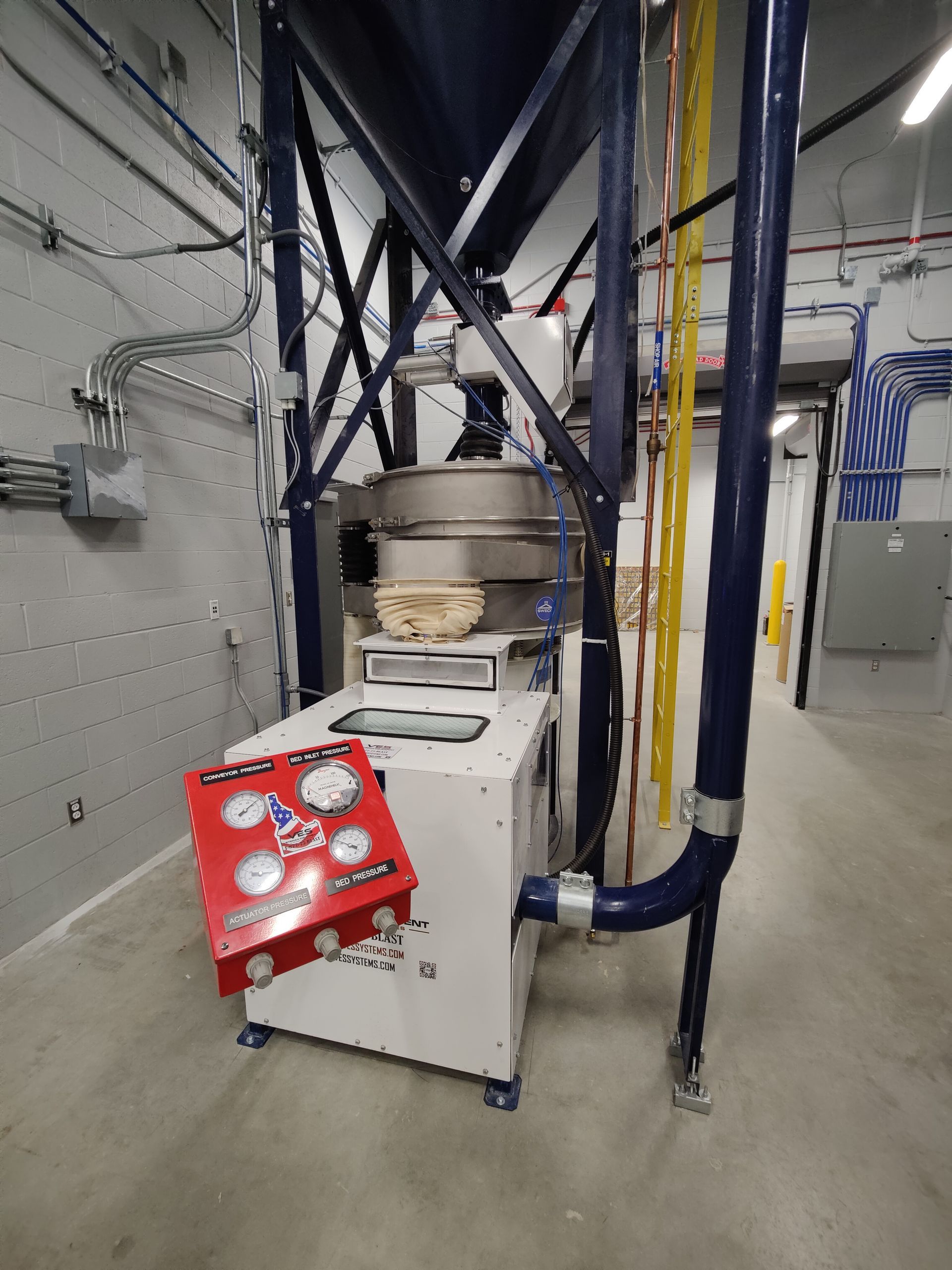 Industrial machine with blue and white components, red control panel, in a utility room.