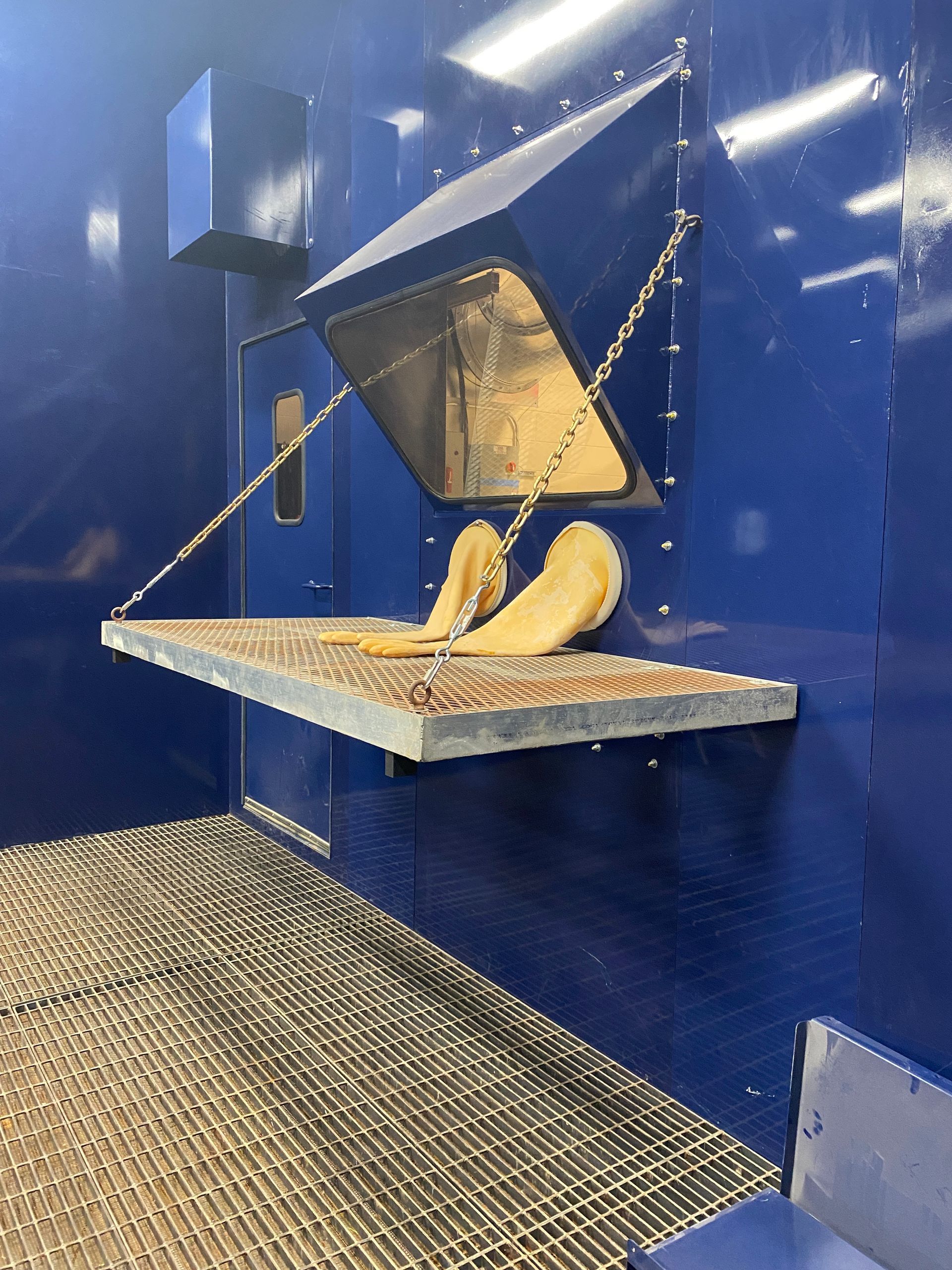 Blue industrial chamber with open access, metal shelf, and hanging pastries.