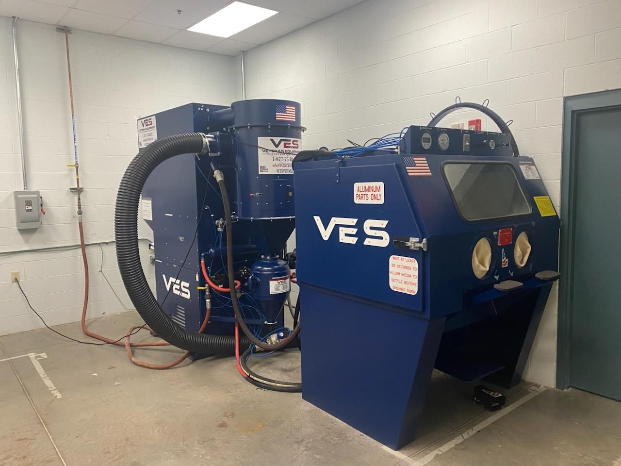 Blue VES sandblasting machine in a white room.
