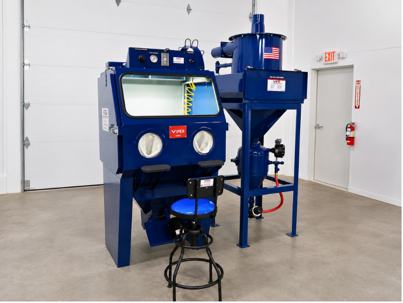 VES Raptor blast cabinet with dust collector, yellow platform, and industrial work area setup.