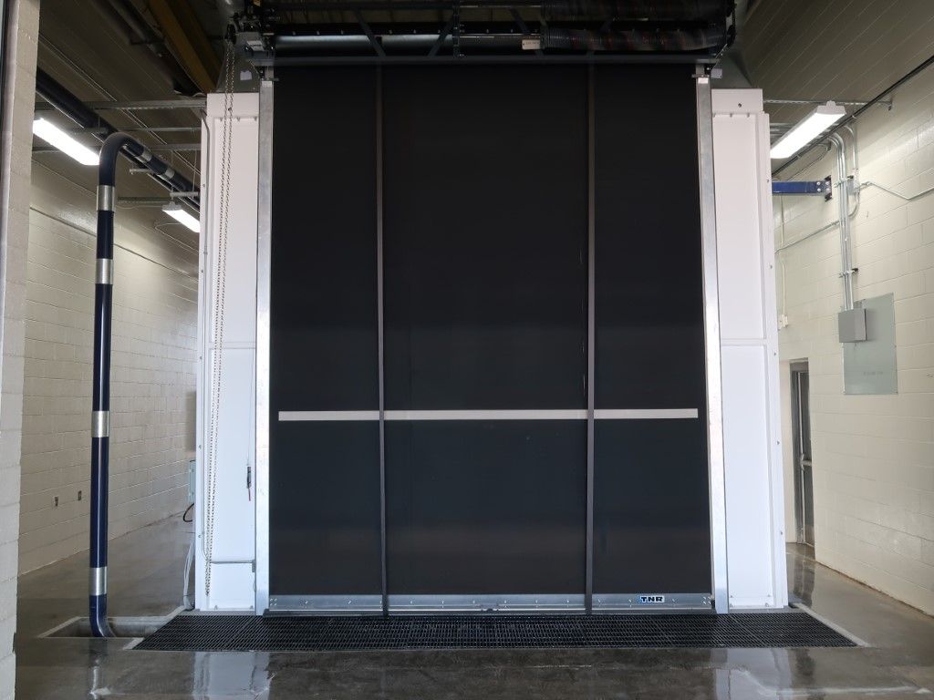 Black roll-up blast booth door.