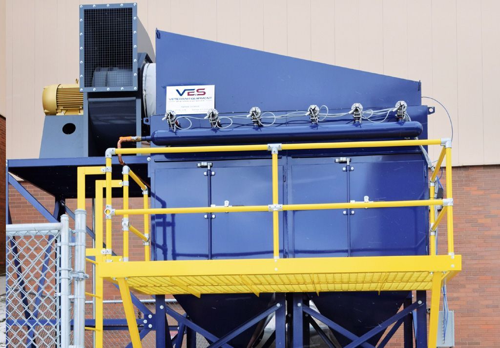Blue industrial dust collector unit with yellow platform and railing, outdoors.