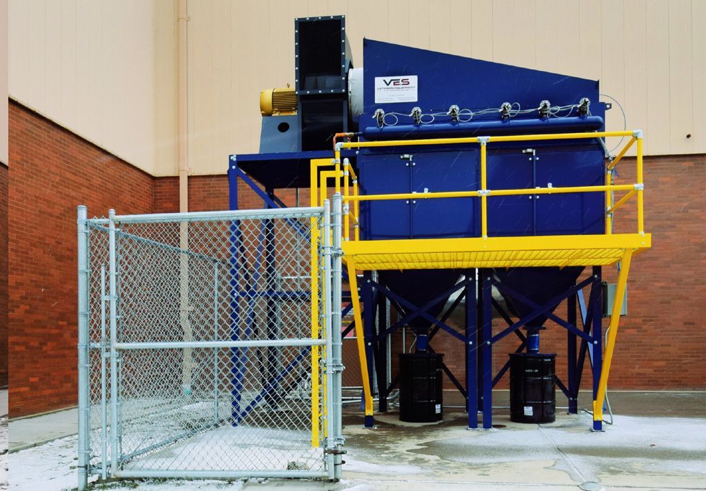 Blue and yellow industrial dust collector with a fenced-in area.