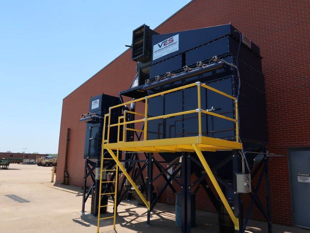 Dust collection system on brick building. Black and yellow with ladder and platform.