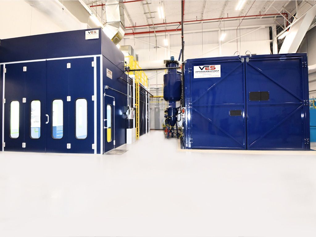 Blue industrial paint booths inside a bright, clean factory setting.