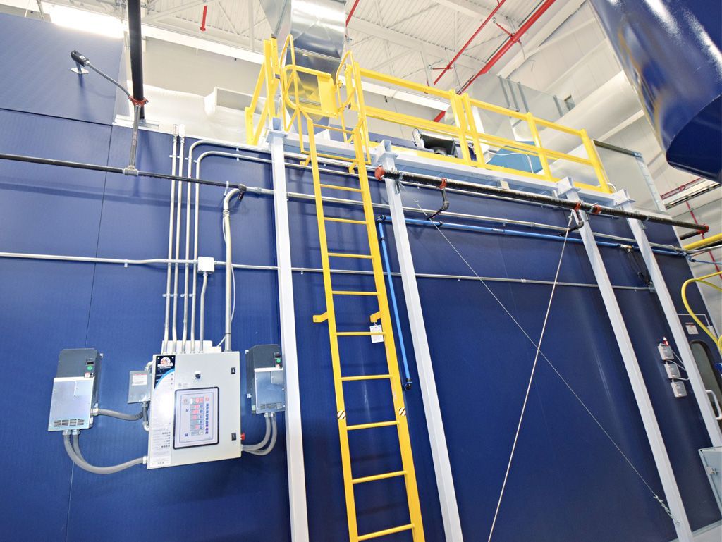 Blue industrial equipment with yellow ladder and safety platform.