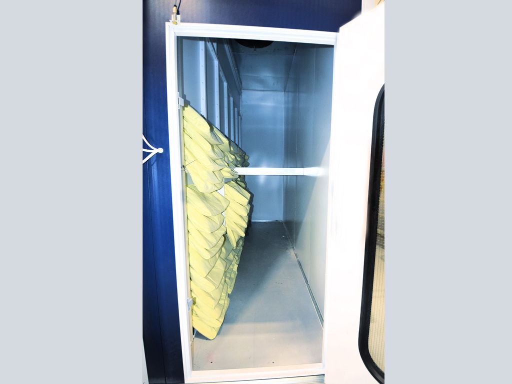 Open door reveals a narrow, white room with yellow acoustic panels hanging from one side.