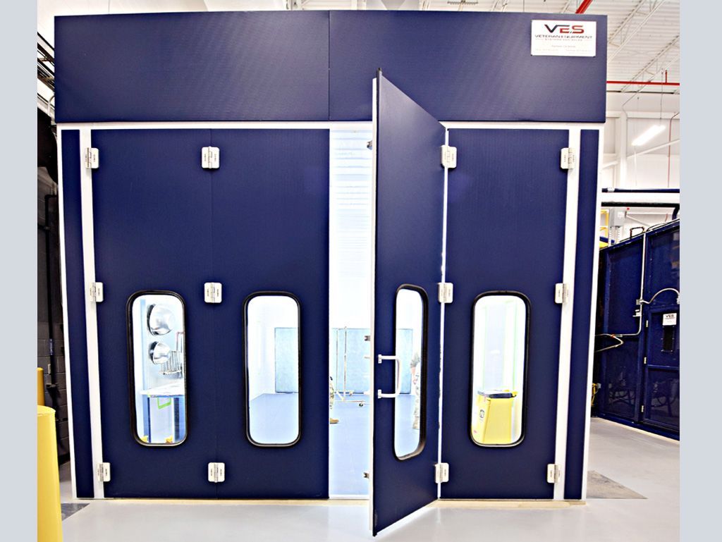 Blue industrial paint booth with open door and window.