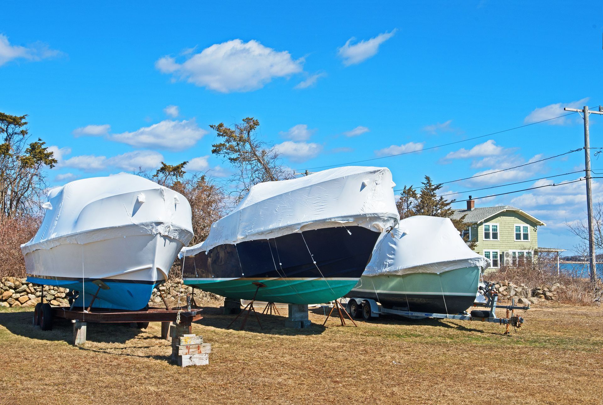 Three small boats on grass covered with white top canvas boat covers