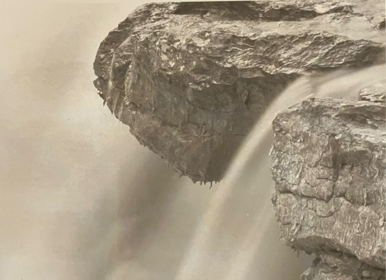 Waterfall cascading over a rocky cliff edge, mist in the air.