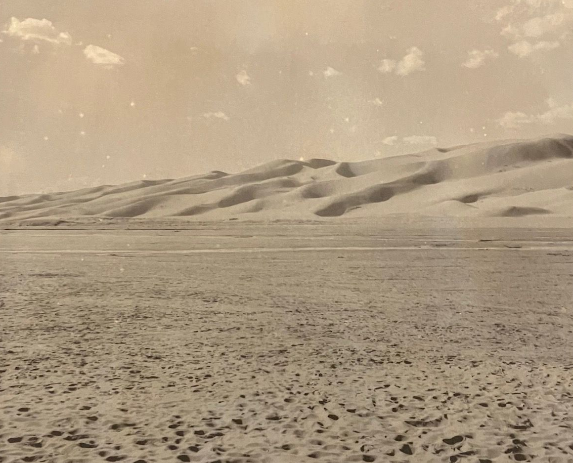 Photography print of a desert landscape: sand dunes under a cloudy sky.